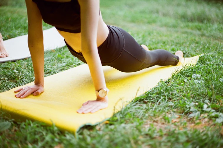 Uma senhora a prtaicar yoga num jardim