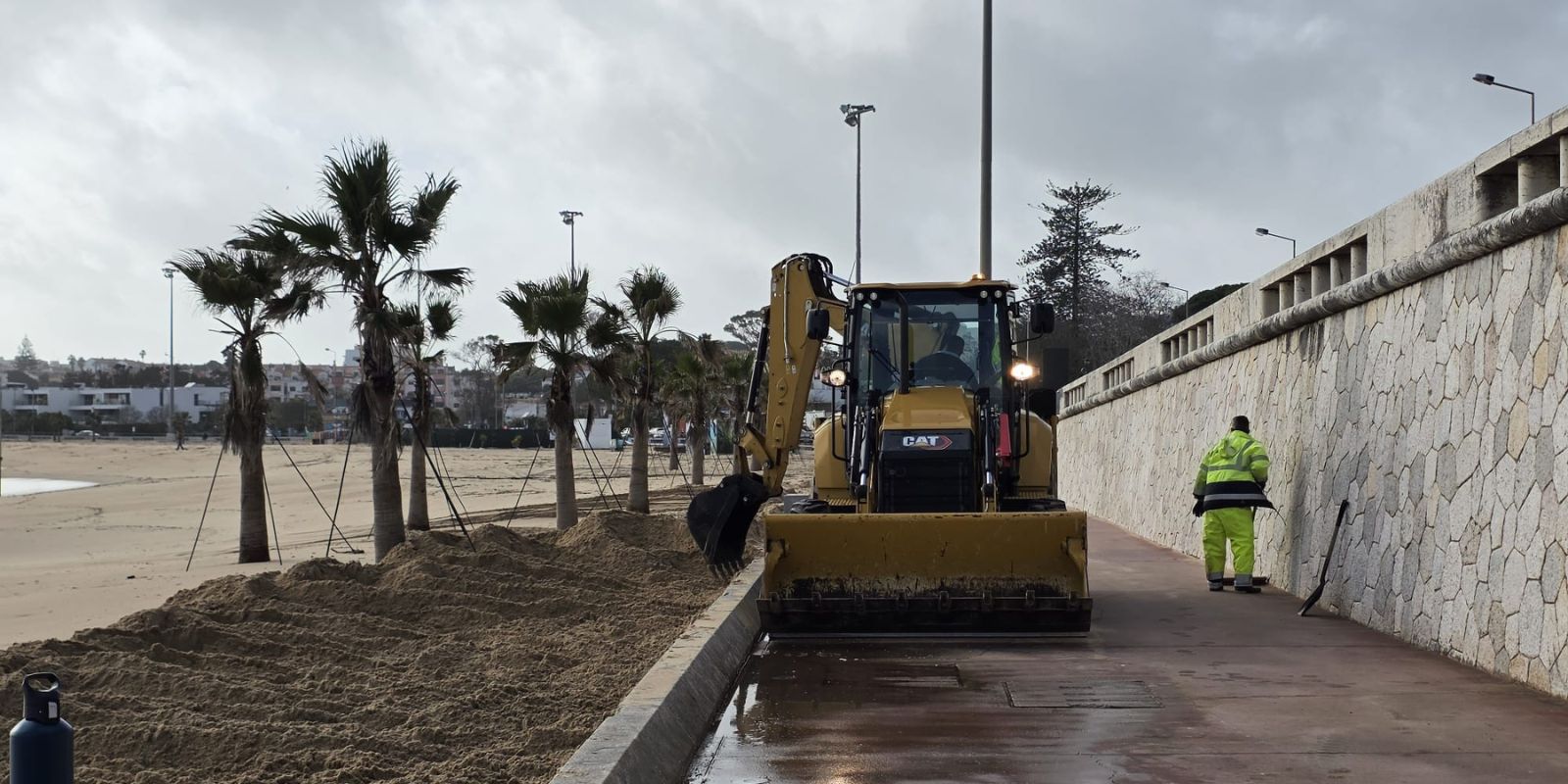 Retroescavadora a remover areia do passeio marítimo