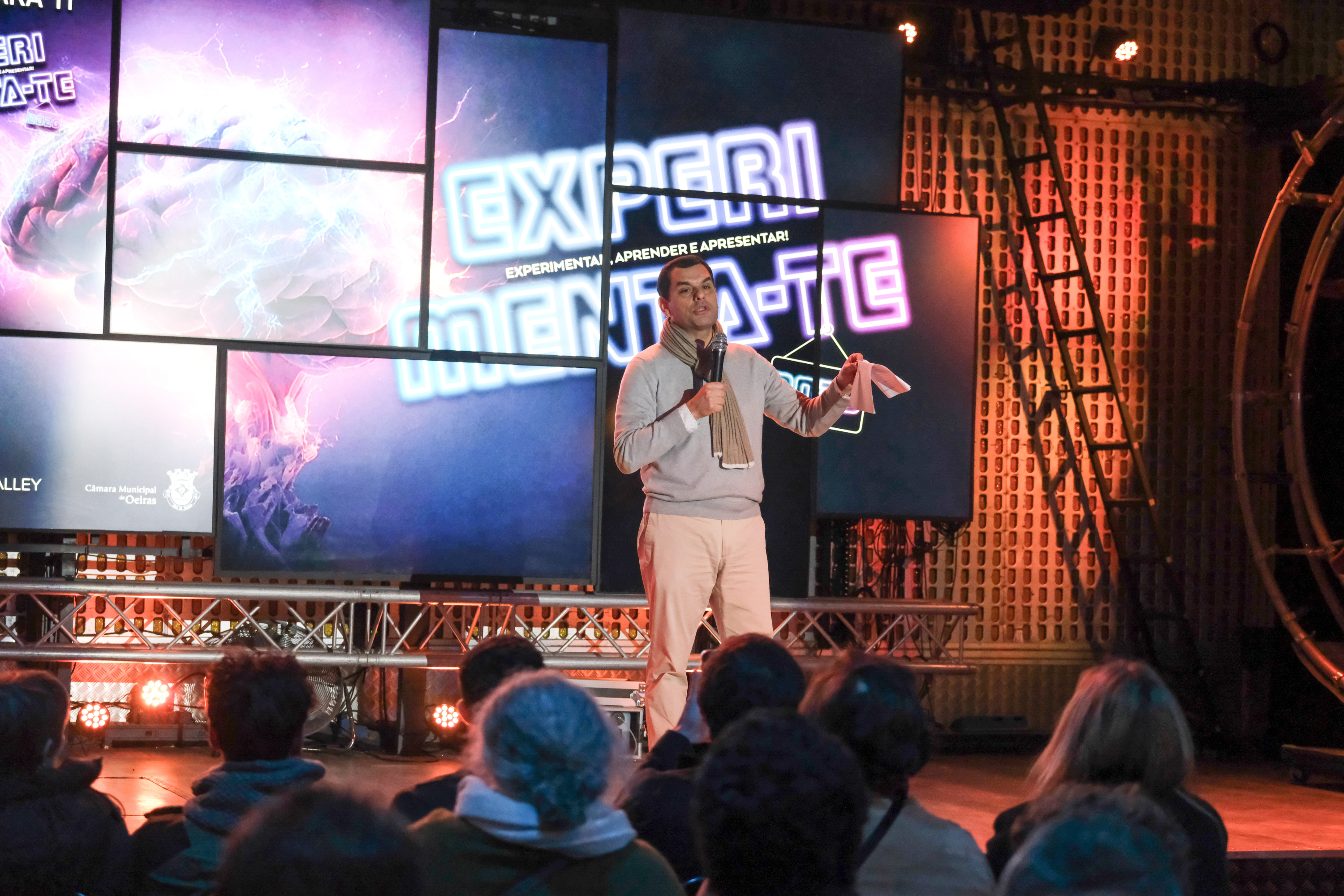 O Vereador Pedro Patacho discursa num palco perante uma plateia, tendo como pano de fundo ecrãs a exibir o logótipo do evento Experimenta-te