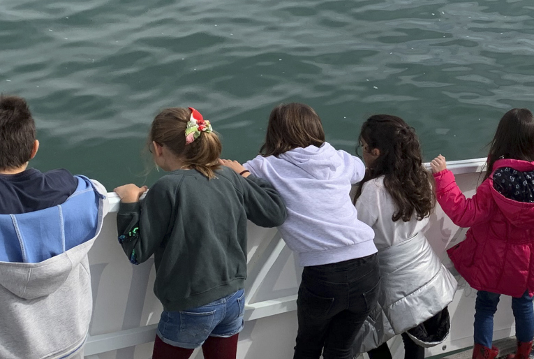 crianças num barco a olhar para o mar
