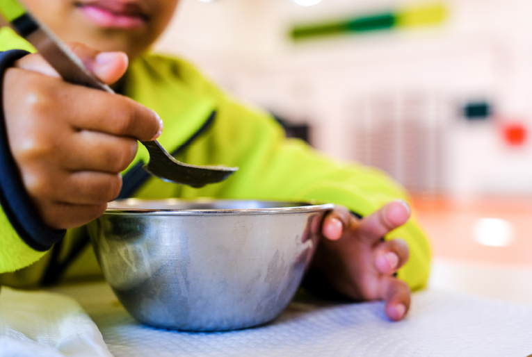 Criança a comer sopa no refeitório escolar
